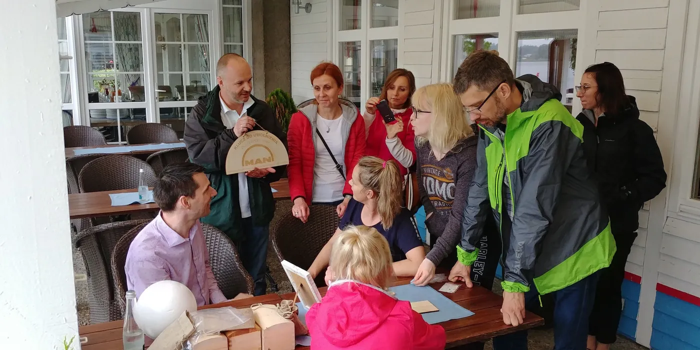 Zespół rozwiązujący zadanie gry przy stole na tarasie nad jeziorem